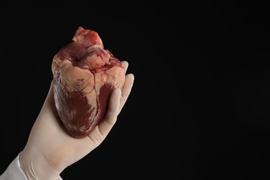 Photo of Doctor with heart on black background, closeup. Space for text