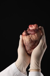 Photo of Doctor with heart on black background, closeup