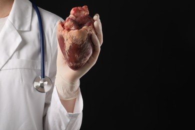 Photo of Doctor with heart on black background, closeup. Space for text