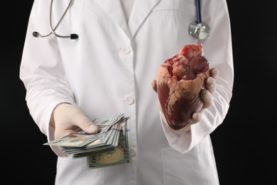 Photo of Doctor with heart and dollar banknotes on black background, closeup