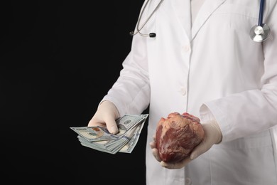 Doctor with heart and dollar banknotes on black background, closeup