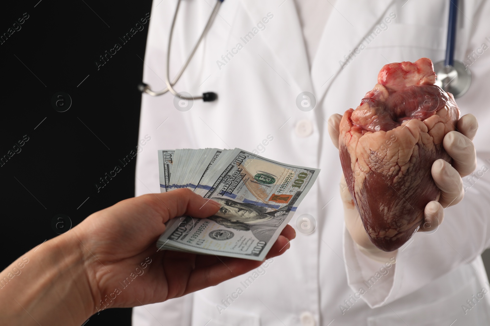 Photo of Patient giving dollar banknotes to doctor with heart on black background, closeup