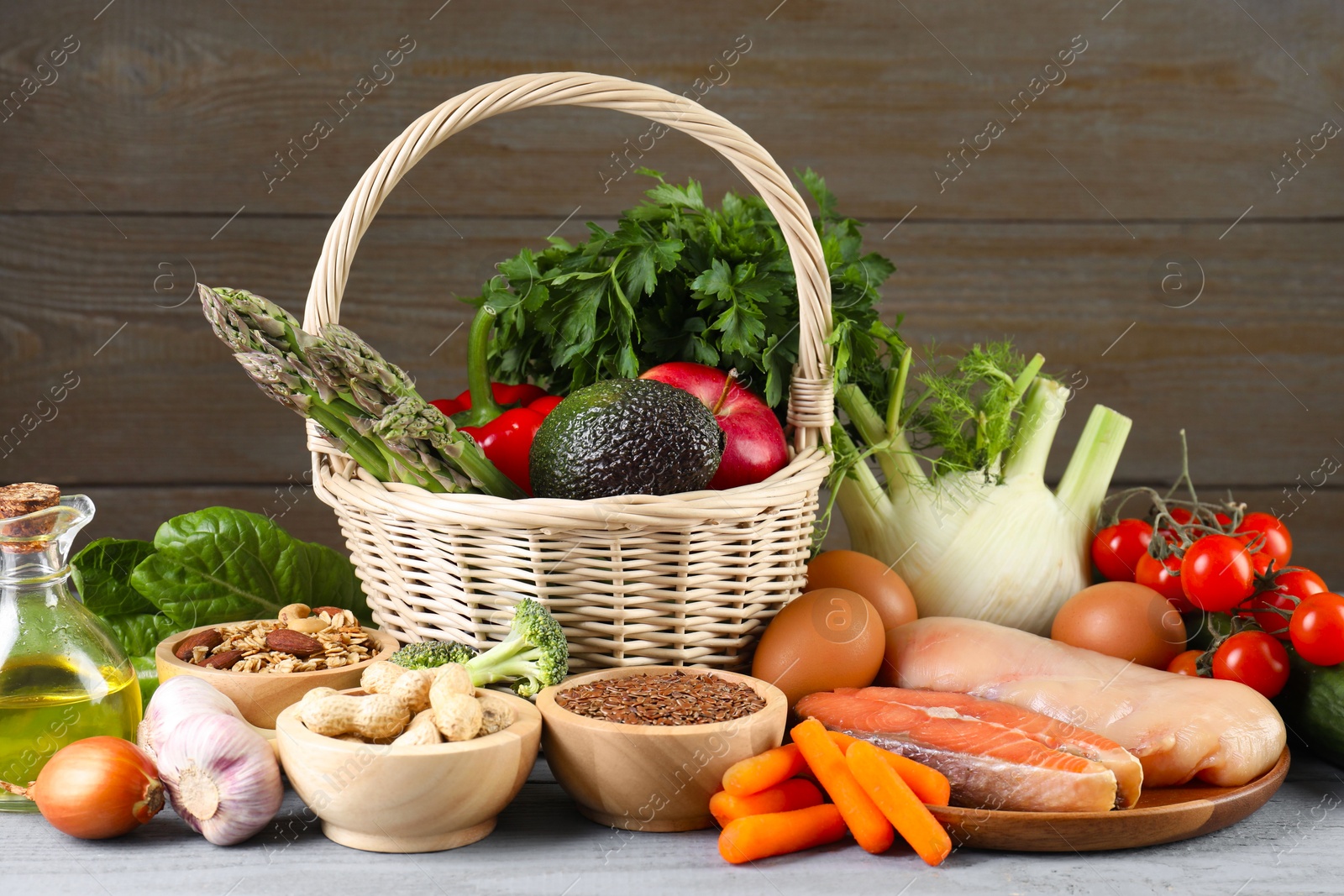 Photo of Healthy food. Basket with different fresh products on grey wooden table