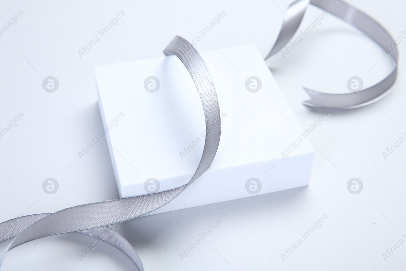 Photo of Beautiful grey ribbon and gift box on white background