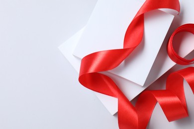 Beautiful red ribbon and gift boxes on white background, top view. Space for text