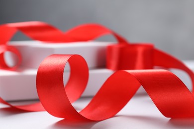 Photo of Beautiful red ribbon on white table, closeup