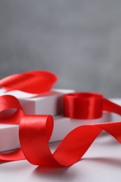 Photo of Beautiful red ribbon and gift boxes on white table