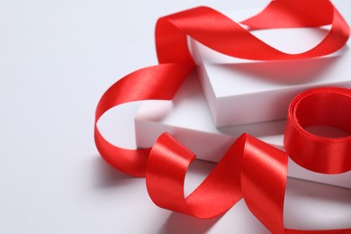 Beautiful red ribbon and gift boxes on white background