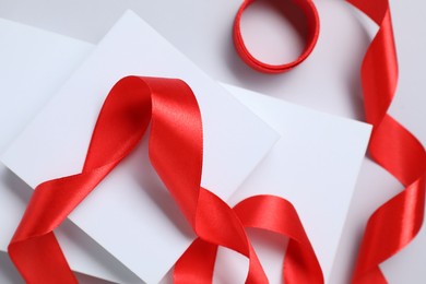 Photo of Beautiful red ribbon and gift boxes on white background, flat lay