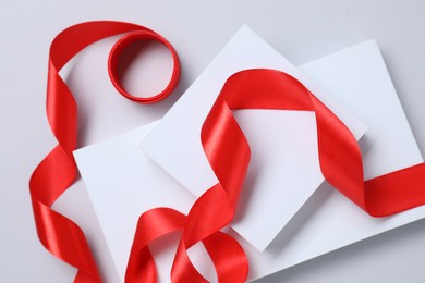 Beautiful red ribbon and gift boxes on white background, flat lay