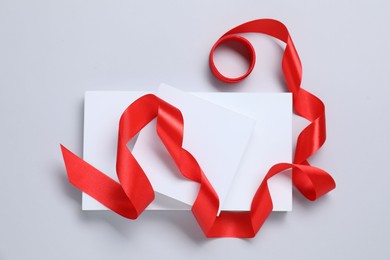 Photo of Beautiful red ribbon and gift boxes on white background, flat lay