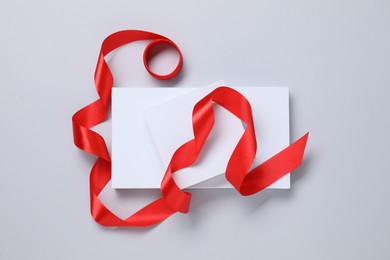 Beautiful red ribbon and gift boxes on white background, flat lay
