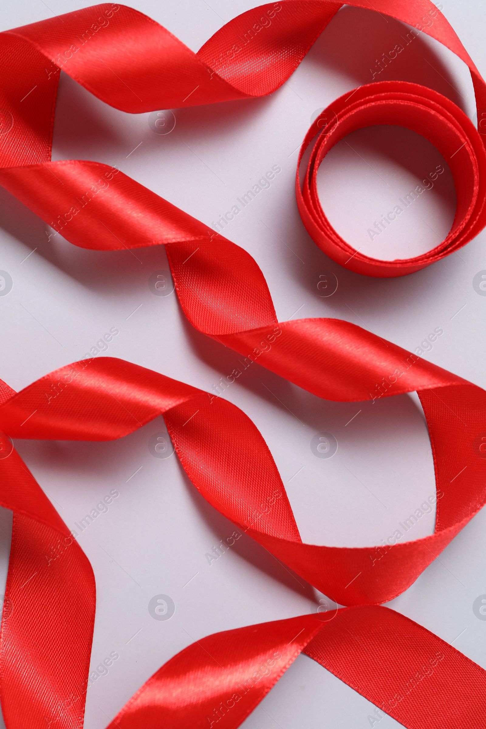 Photo of One beautiful red ribbon on white background, top view