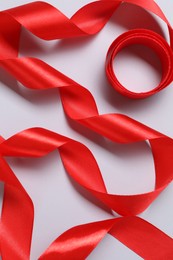 Photo of One beautiful red ribbon on white background, top view