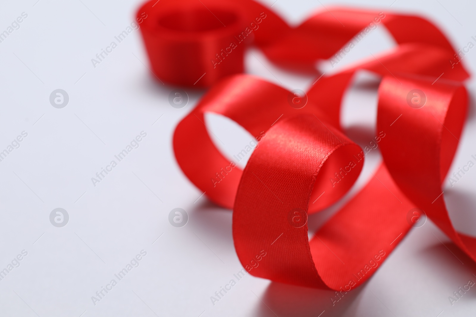 Photo of One beautiful red ribbon on white background, closeup. Space for text