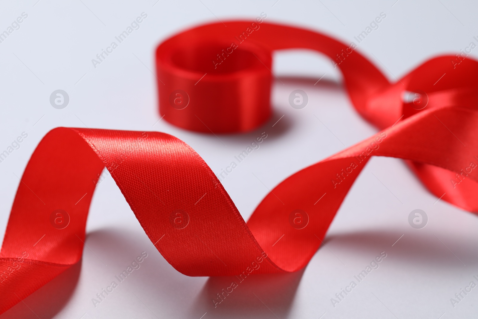 Photo of One beautiful red ribbon on white background, closeup