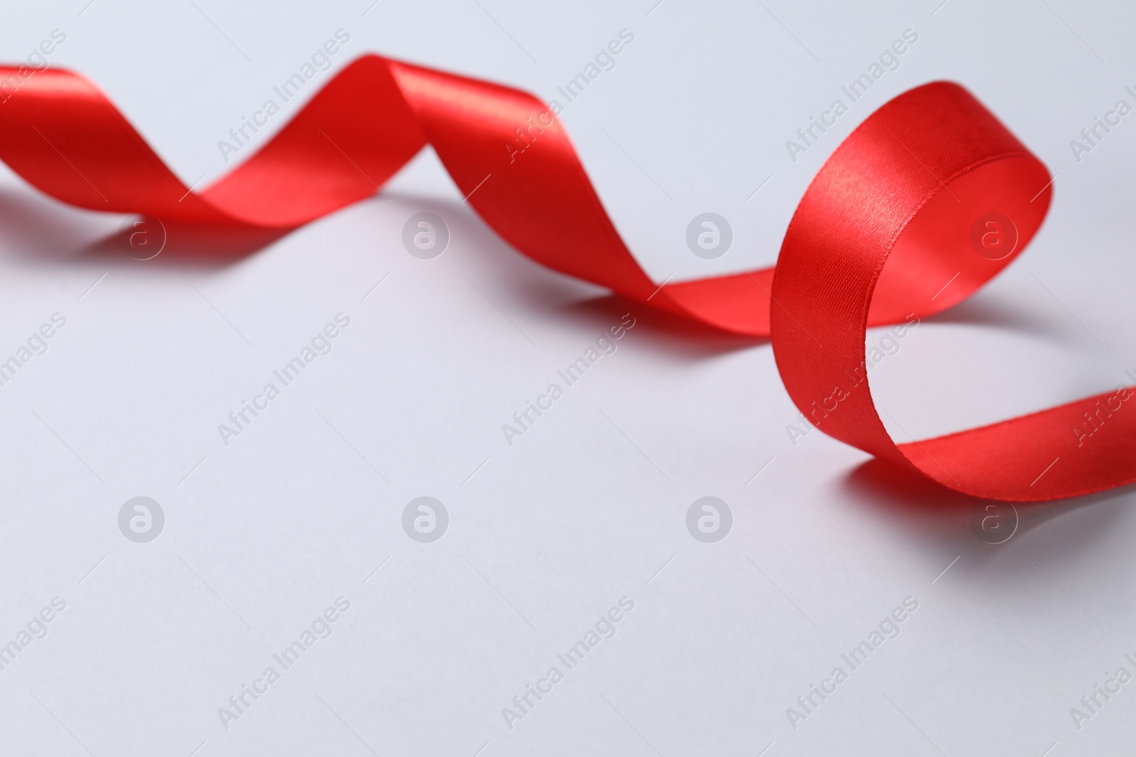 Photo of One beautiful red ribbon on white background, space for text