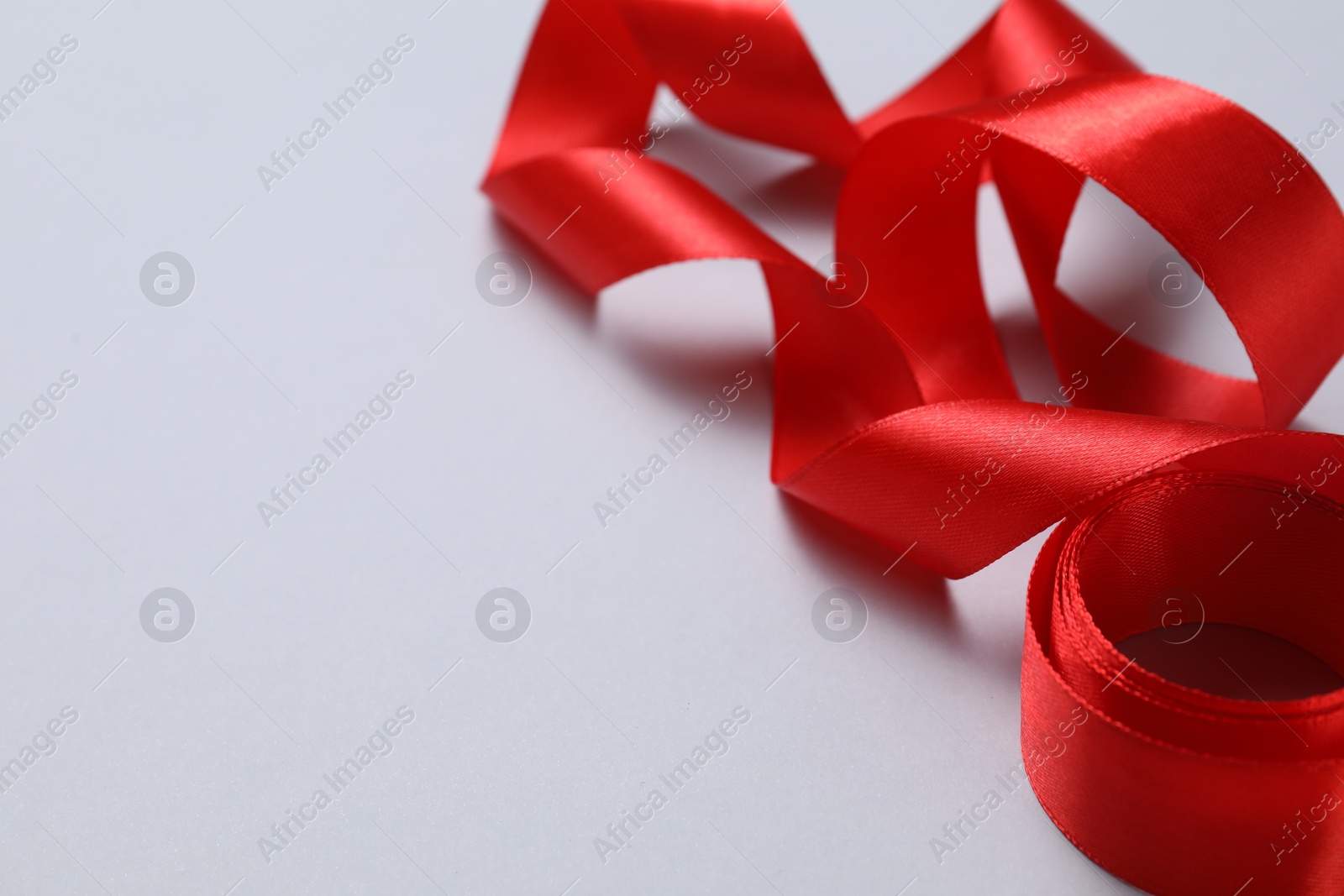 Photo of One beautiful red ribbon on white background, closeup. Space for text