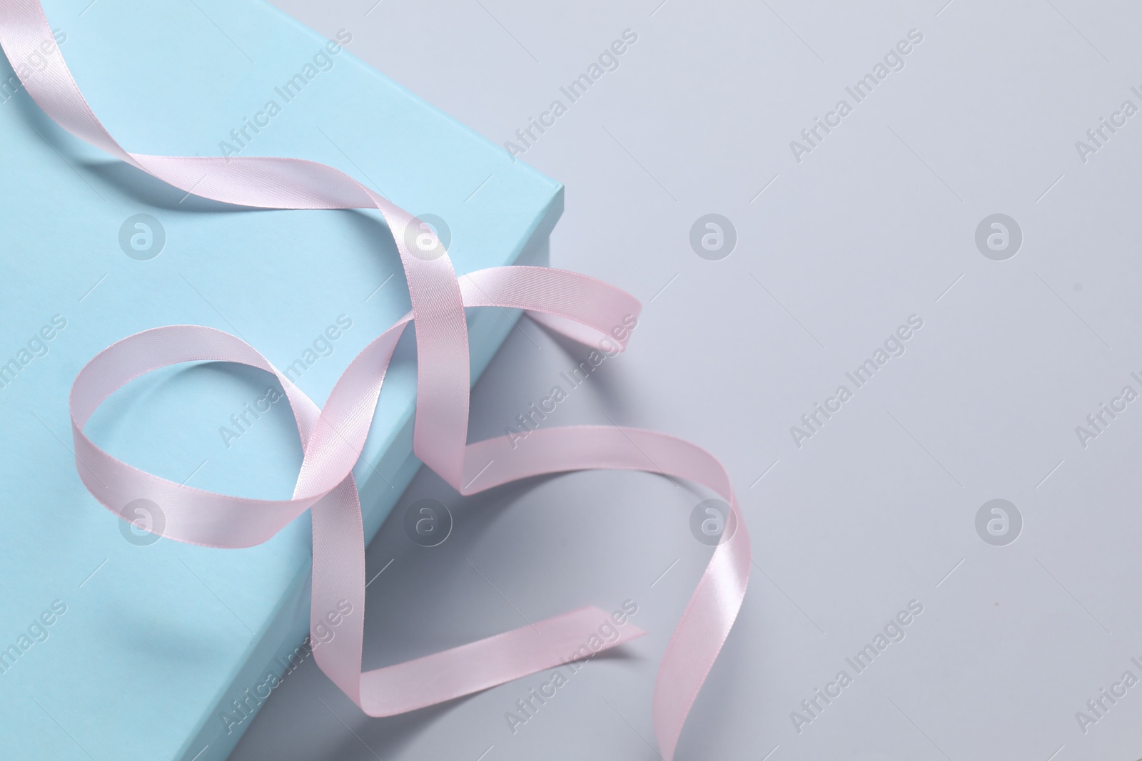 Photo of Beautiful pink ribbon and gift box on white background, above view. Space for text