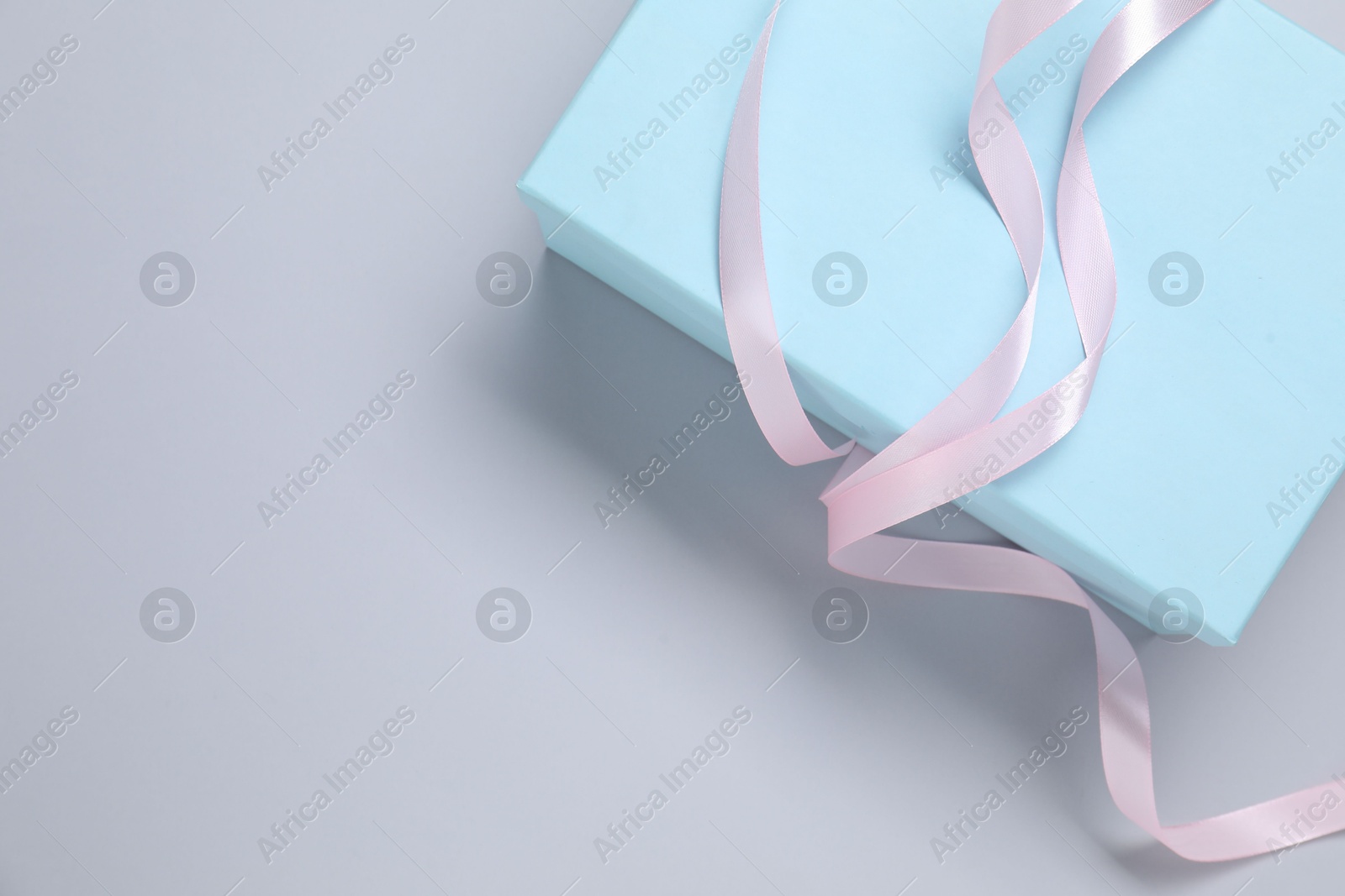 Photo of Beautiful pink ribbon and gift box on white background, top view. Space for text