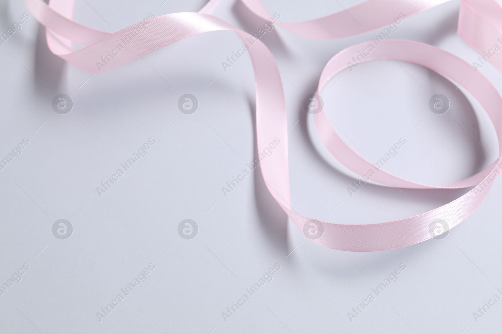 Photo of One beautiful pink ribbon on white background, space for text