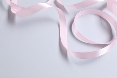 One beautiful pink ribbon on white background, space for text