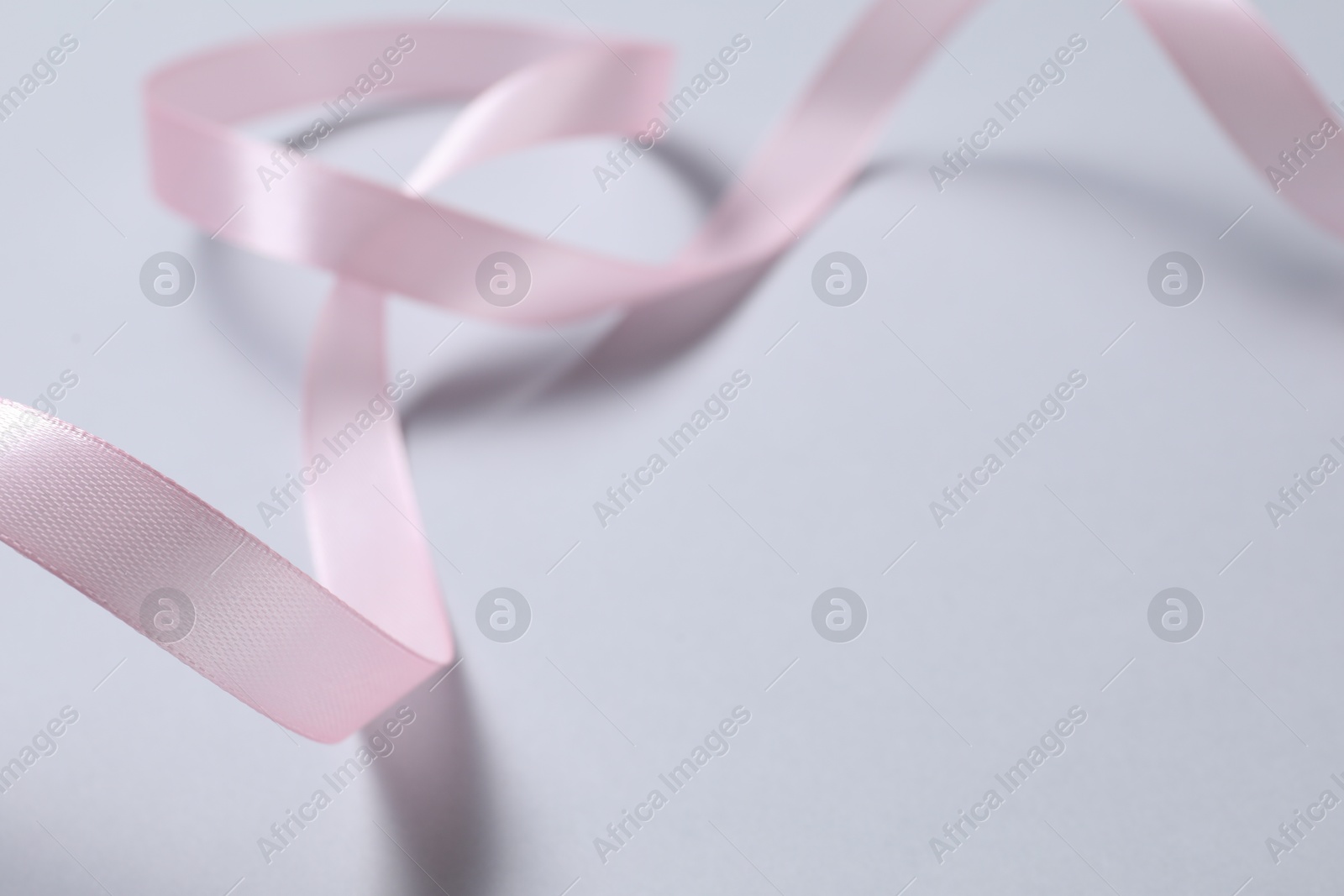 Photo of One beautiful pink ribbon on white background, space for text