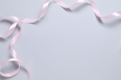 One beautiful pink ribbon on white background, top view. Space for text