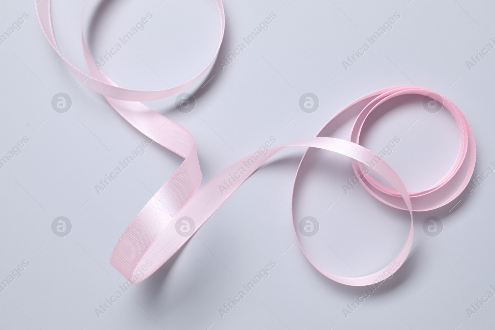 Photo of One beautiful pink ribbon on white background, top view