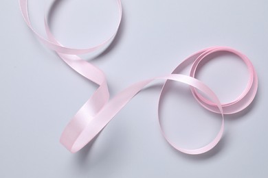 One beautiful pink ribbon on white background, top view