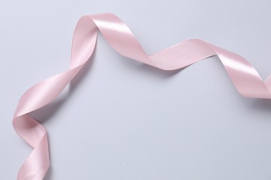 Photo of One beautiful pink ribbon on white background, top view. Space for text