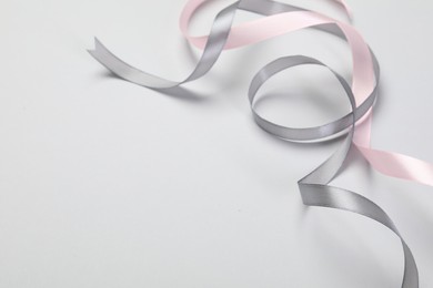 Beautiful grey and pink ribbons on white background, space for text