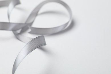 One beautiful grey ribbon on white background, closeup. Space for text