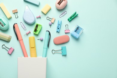 Flat lay composition with holder and different stationery on turquoise background, space for text