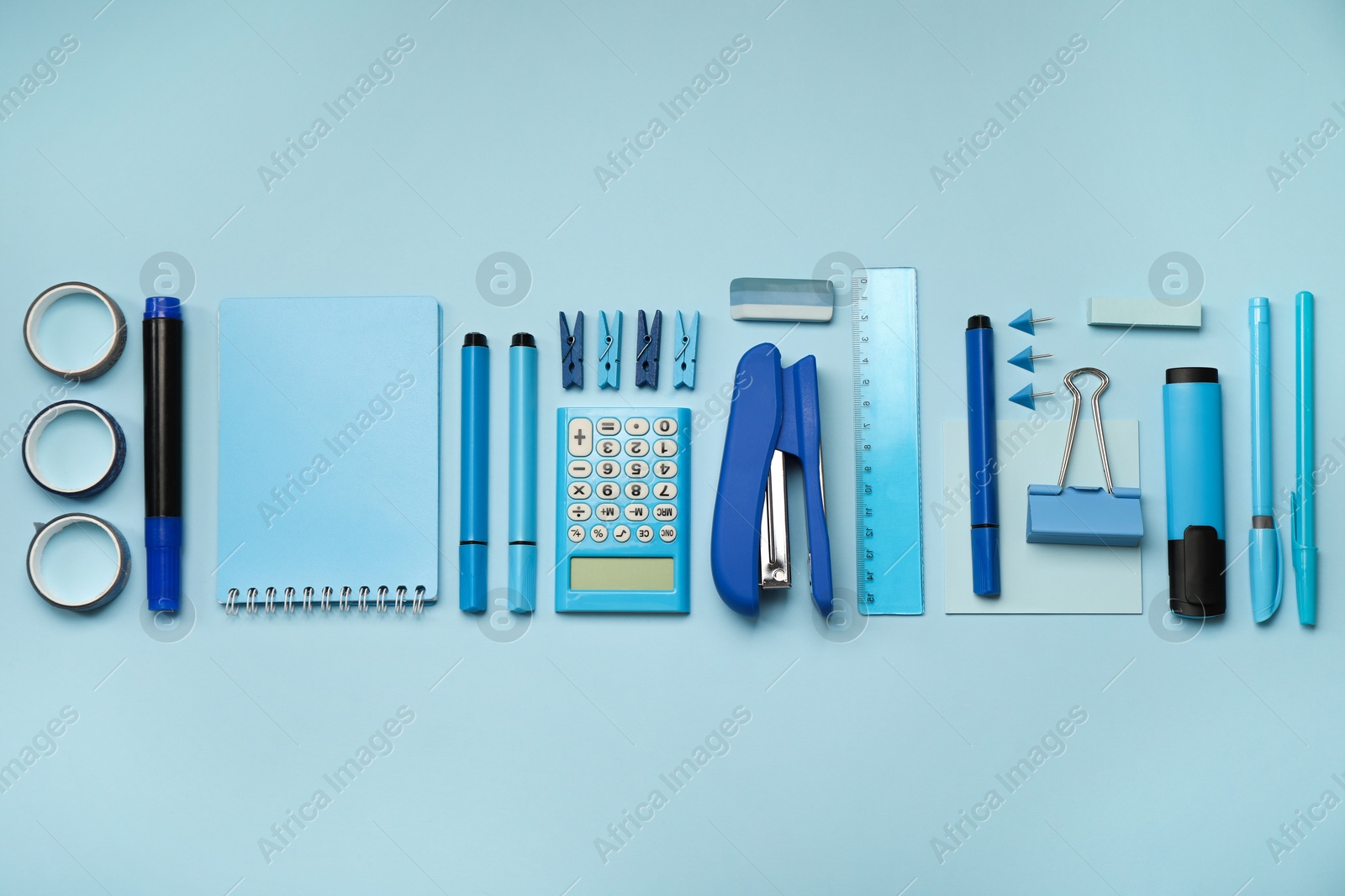 Photo of Flat lay composition with notebook, stapler and different stationery on light blue background