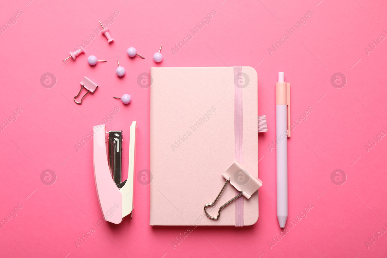 Photo of Flat lay composition with notebook, stapler different stationery on pink background