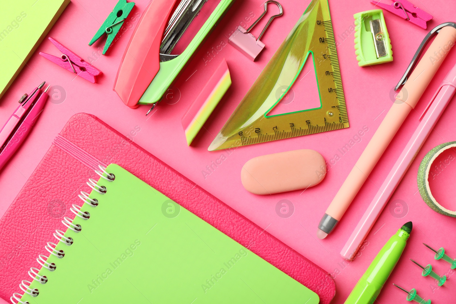 Photo of Flat lay composition with notebooks, stapler and different stationery on pink background