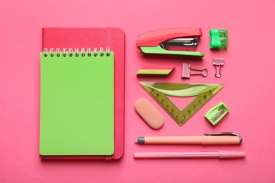 Photo of Flat lay composition with notebooks, stapler and different stationery on pink background