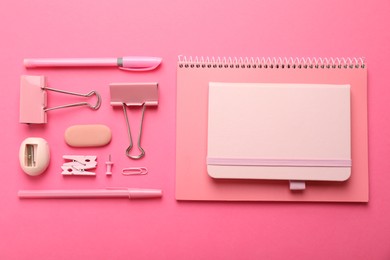 Flat lay composition with notebooks and different stationery on pink background