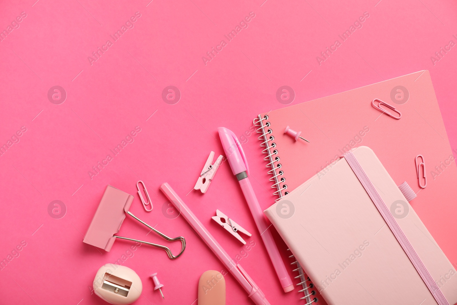 Photo of Flat lay composition with notebooks and different stationery on pink background, space for text