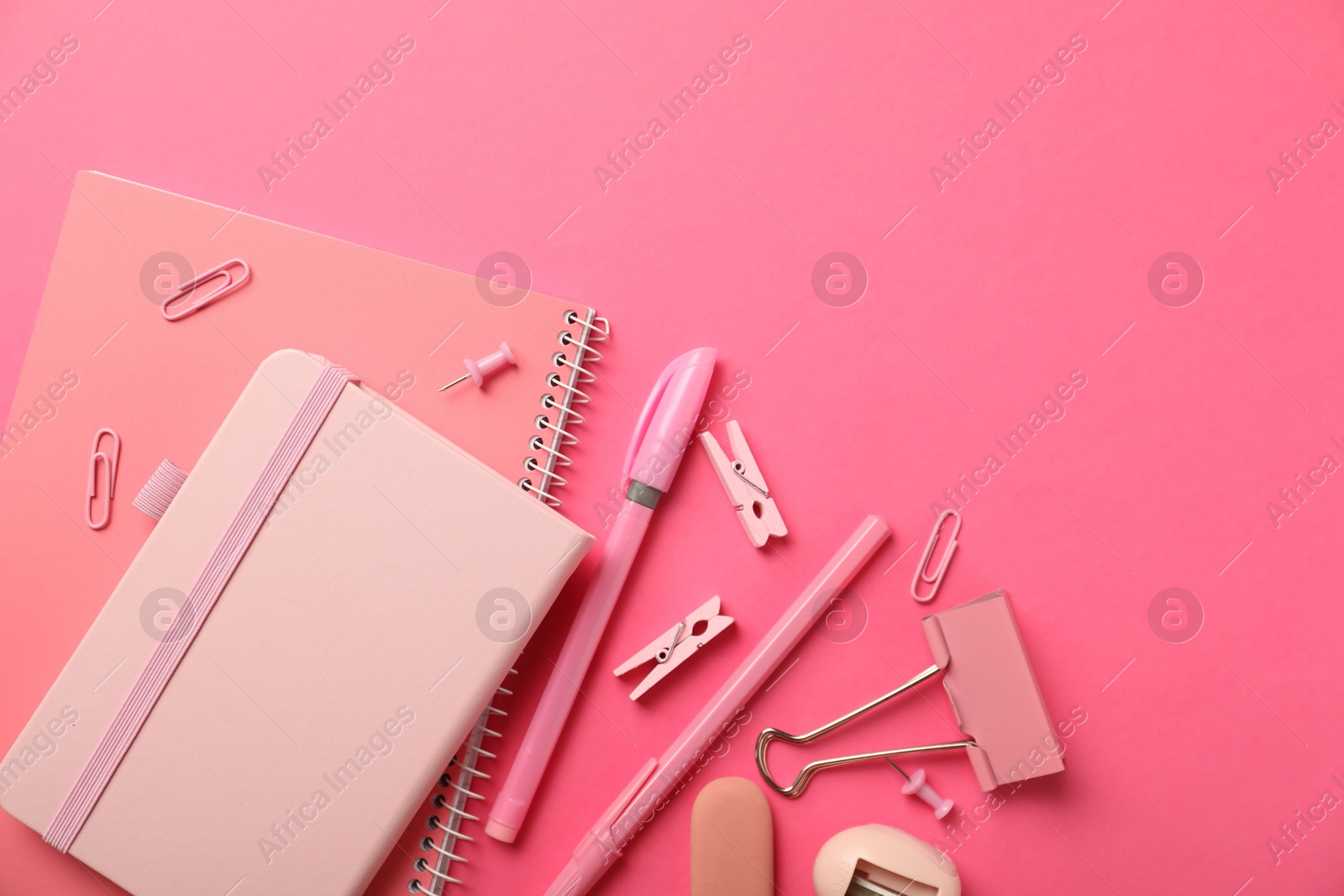 Photo of Flat lay composition with notebooks and different stationery on pink background, space for text