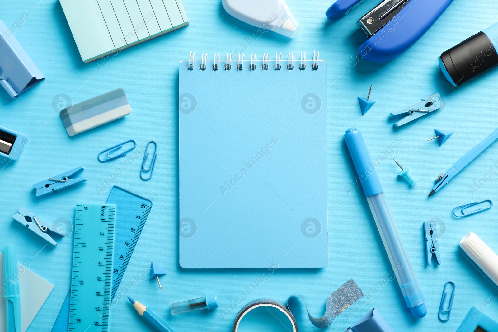 Photo of Flat lay composition with notebook, stapler and different stationery on light blue background