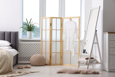 Photo of Folding screen, pouffe, mirror and bed in bedroom