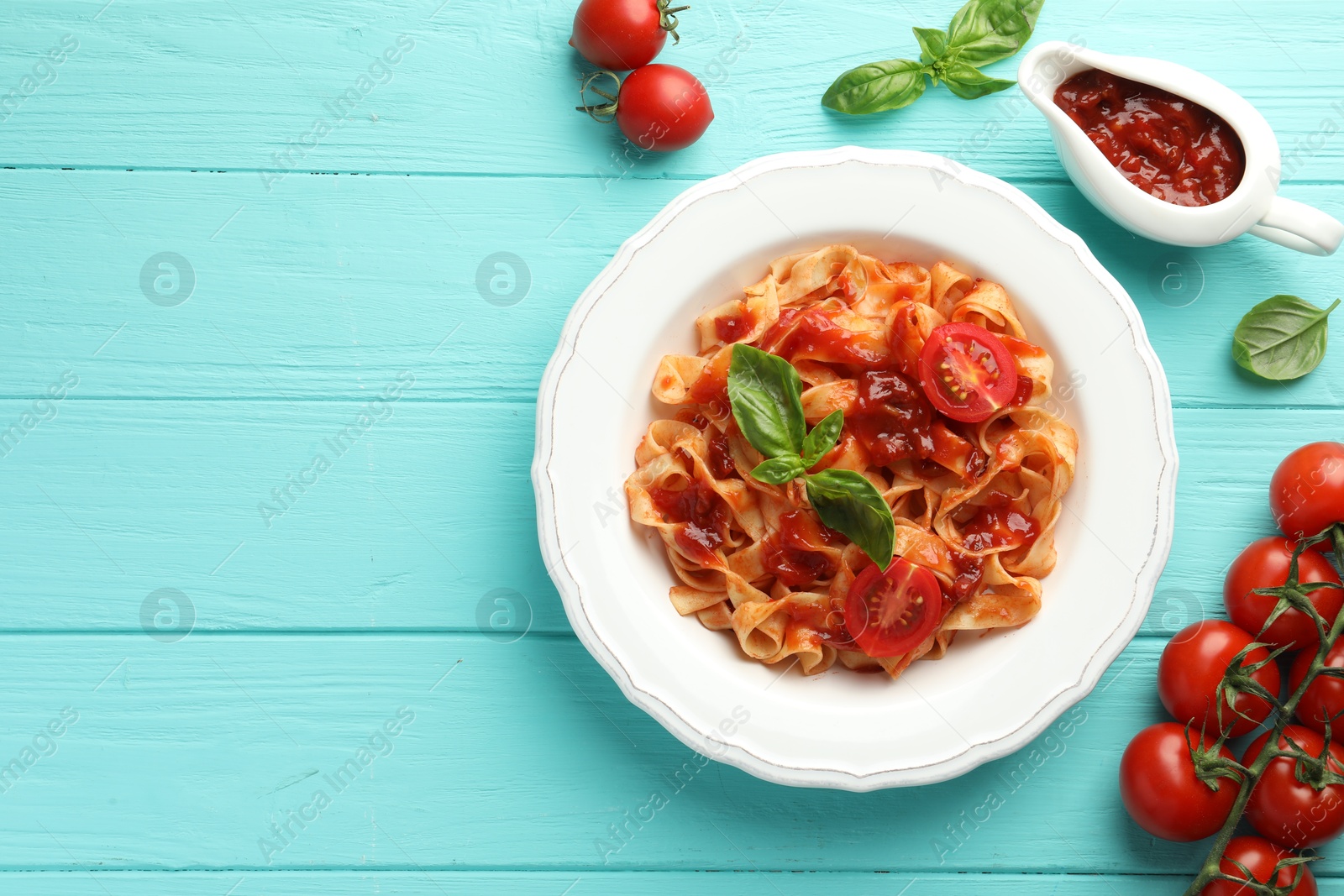 Photo of Delicious pasta with tomato sauce and basil on turquoise wooden table, flat lay. Space for text