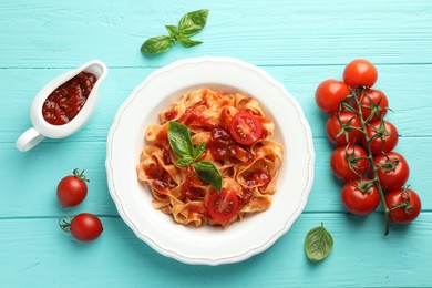 Photo of Delicious pasta with tomato sauce and basil on turquoise wooden table, flat lay