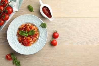 Photo of Delicious pasta with sauce, tomato and basil on wooden table, flat lay. Space for text