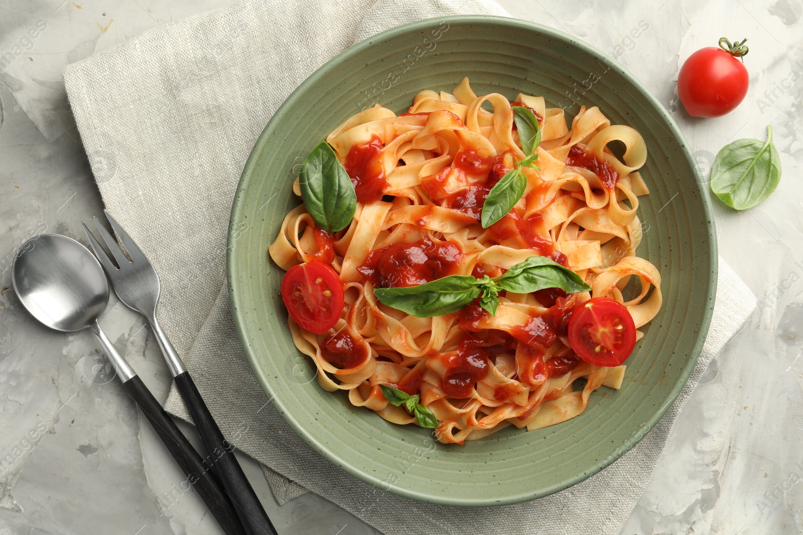 Photo of Delicious pasta with tomato sauce and basil served on grey textured table, flat lay