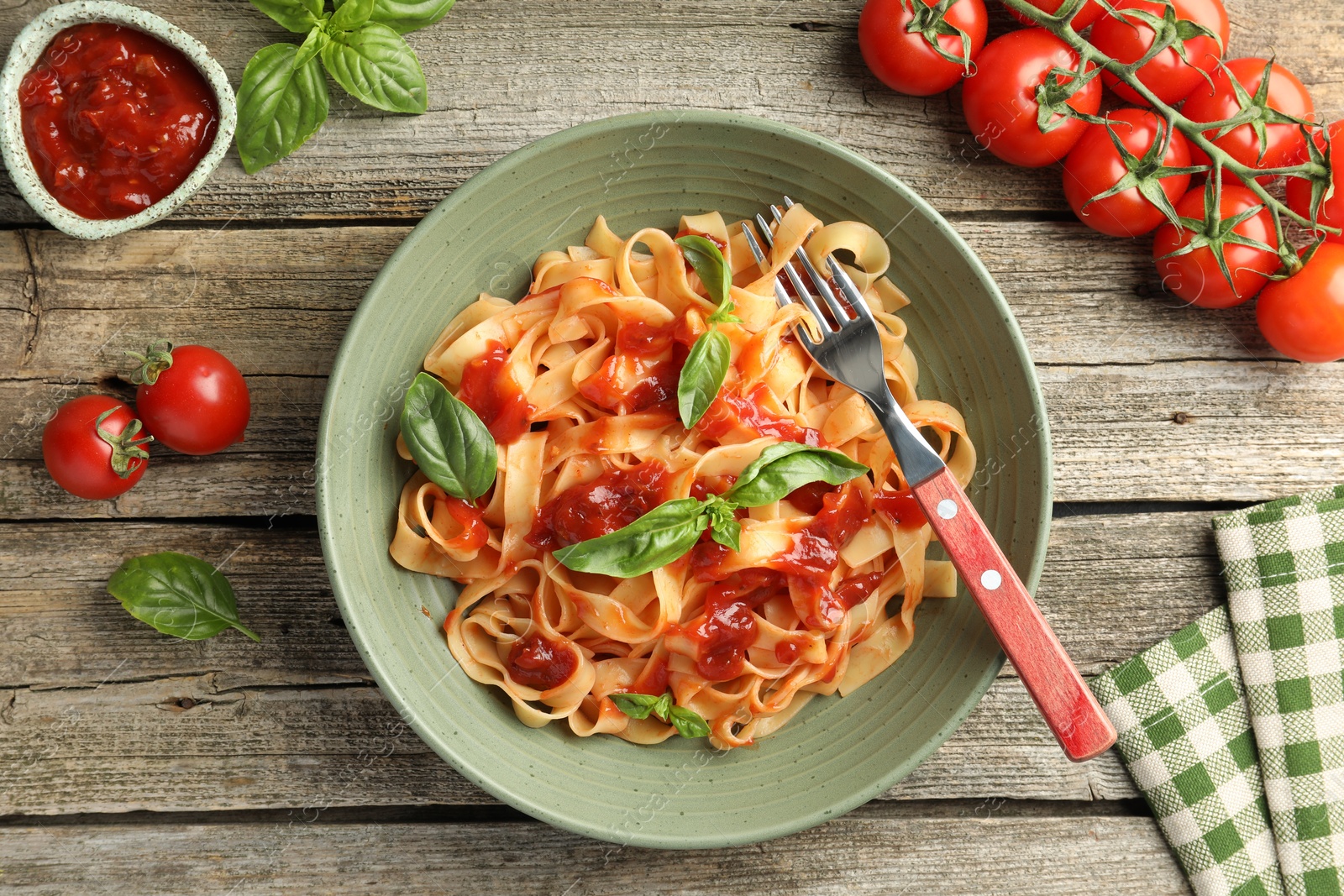 Photo of Delicious pasta with tomato sauce and basil on wooden table, flat lay