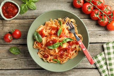 Photo of Delicious pasta with tomato sauce and basil on wooden table, flat lay