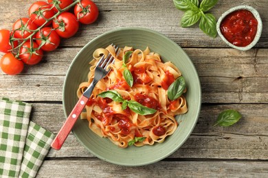 Photo of Delicious pasta with tomato sauce and basil on wooden table, flat lay